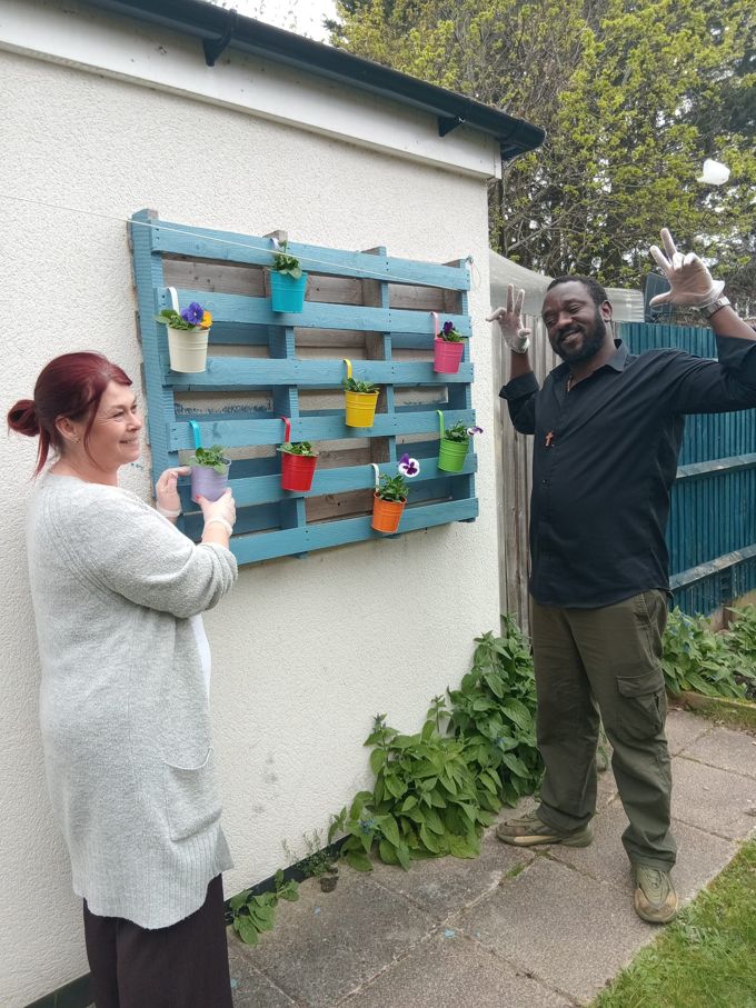 People we support planting flowers on the garden pallet wall